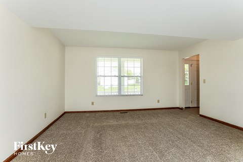 a master bedroom with carpet and white walls and a window
