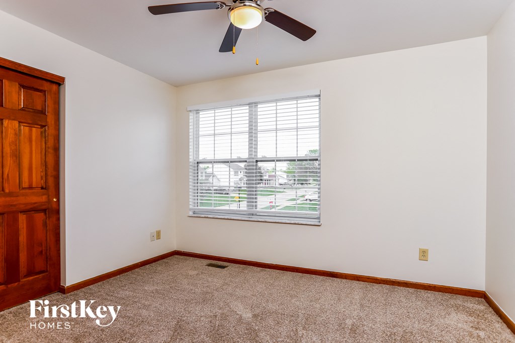 a bedroom with a large window and a ceiling fan