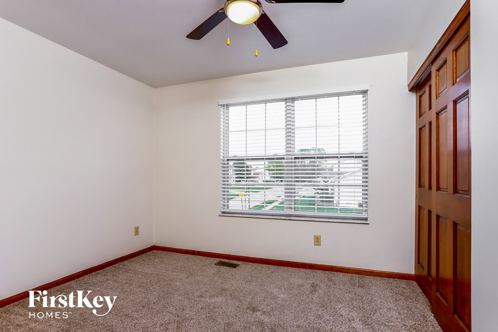 a bedroom with a large window and a ceiling fan