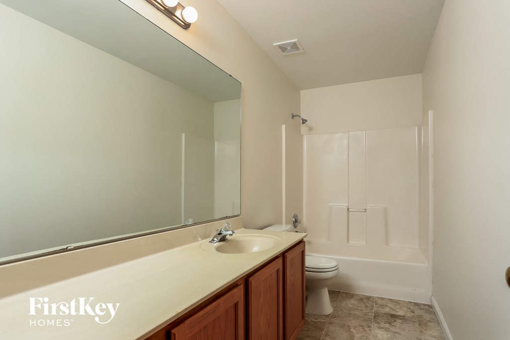 a bathroom with a large mirror and a sink and a toilet