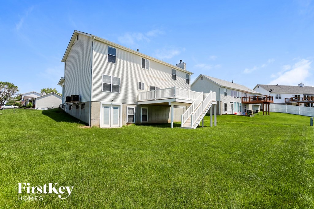a white house with a deck and a staircase in the grass