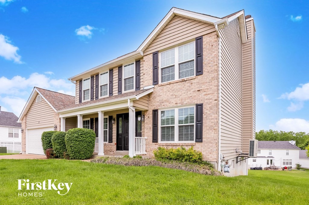 a brick house with tan siding and black shutters