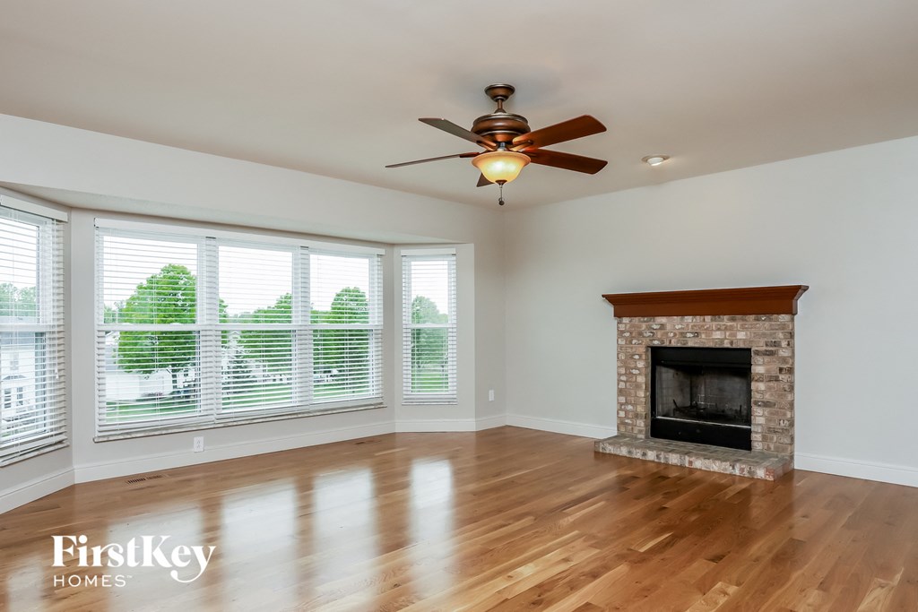 an empty living room with a fireplace and a ceiling fan
