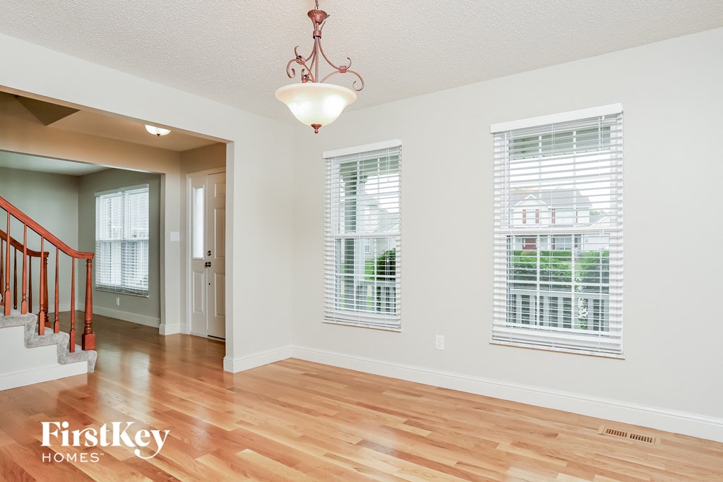 an empty living room with a hardwood floor and windows