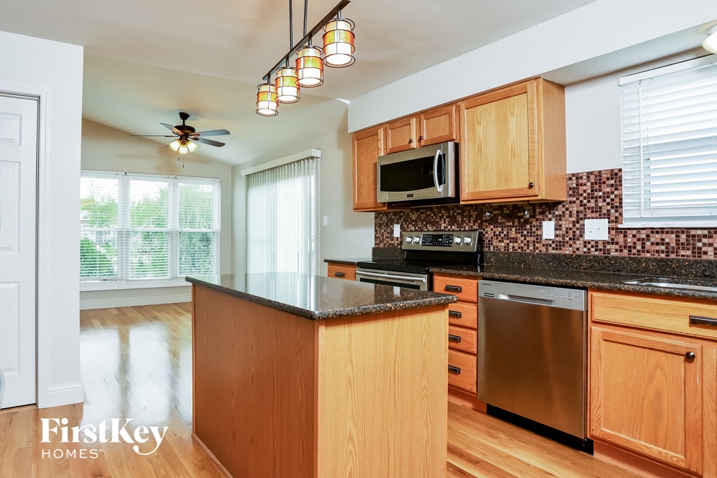 a kitchen with wooden cabinets and black counter tops and a stainless steel dishwasher