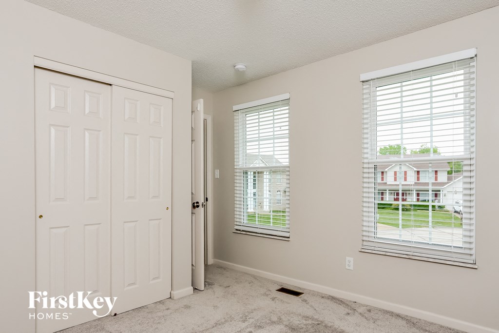 a bedroom with a white door and two windows