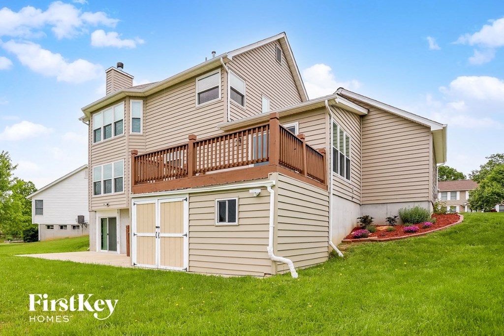 a yellow house with a deck on top of a yard