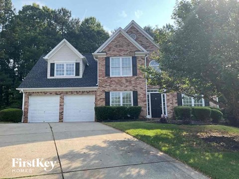 a brick house with white garage doors and a driveway