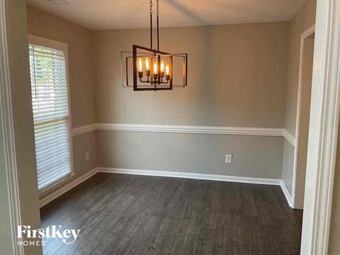 an empty dining room with wood floors and a chandelier