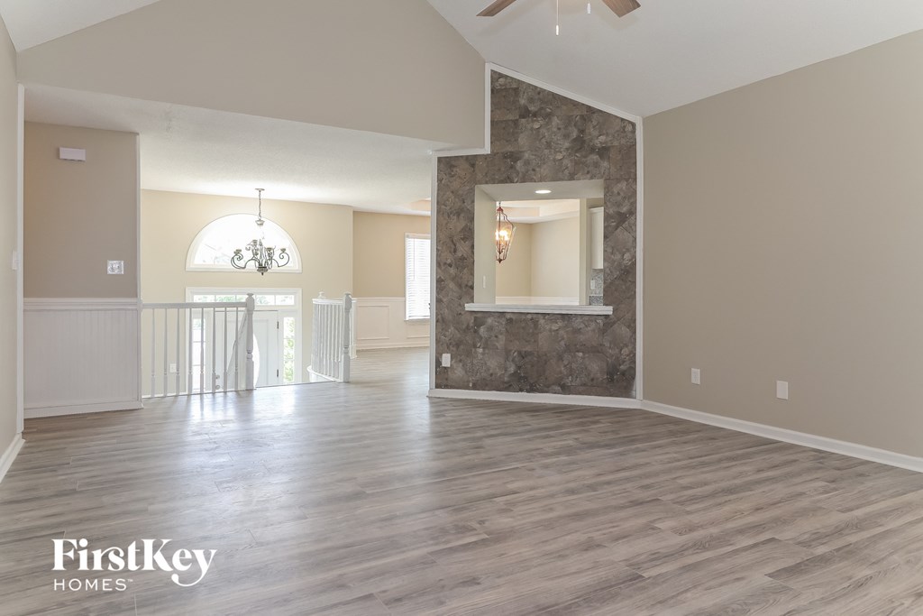 an empty living room with a stone wall and a balcony