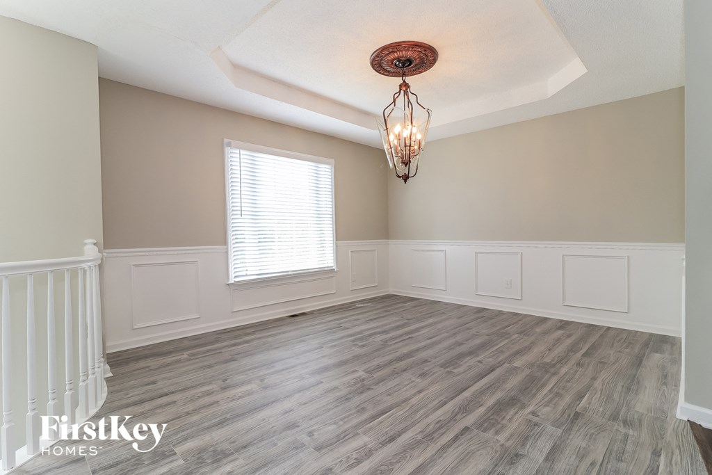 an empty living room with wood floors and a chandelier