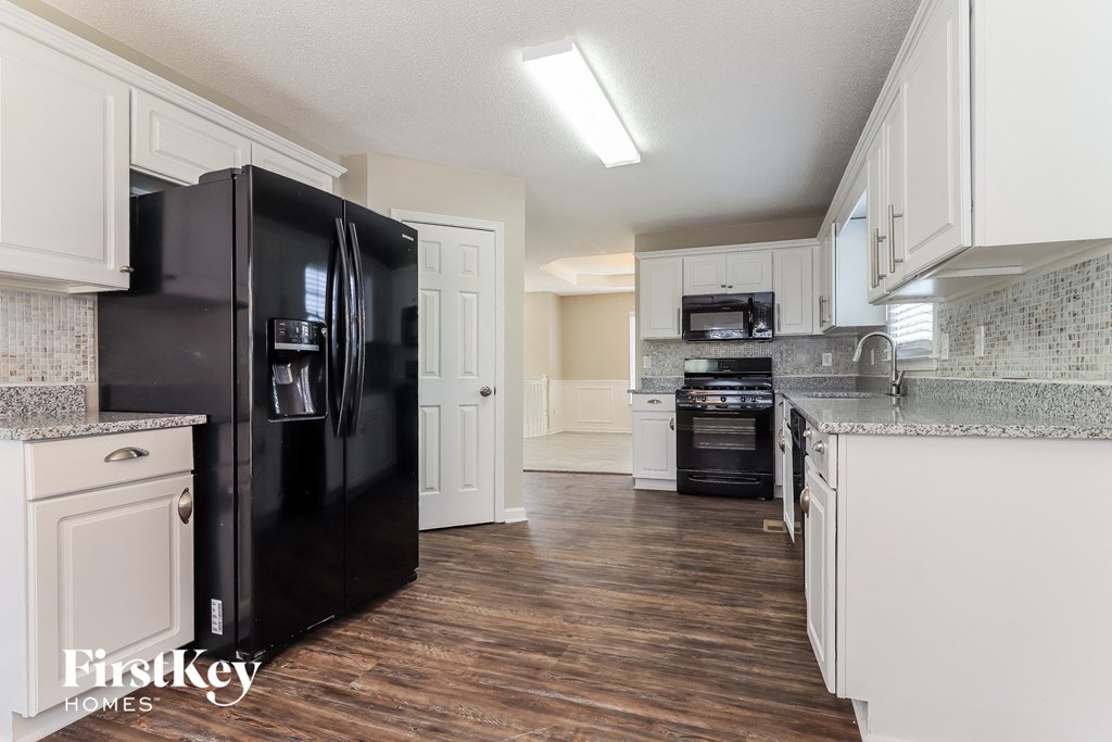 a kitchen with white cabinets and a black refrigerator