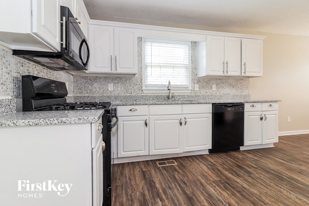 a kitchen with white cabinets and granite counter tops and a black dishwasher