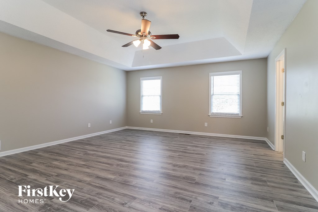 the spacious living room with wood floors and a ceiling fan
