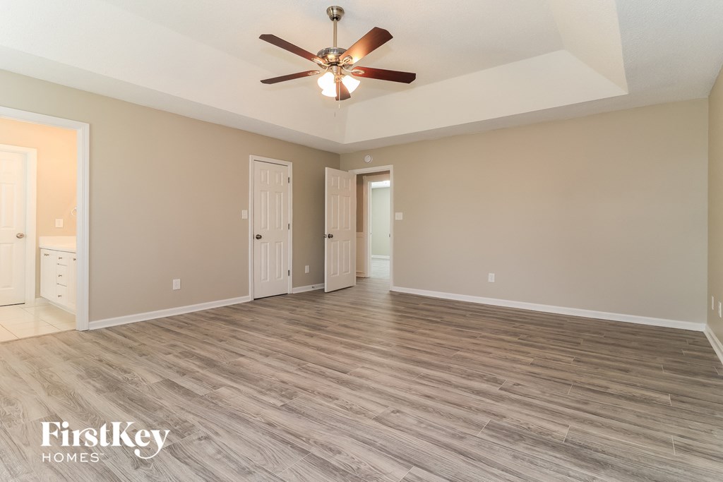 the spacious living room with hardwood floors and a ceiling fan