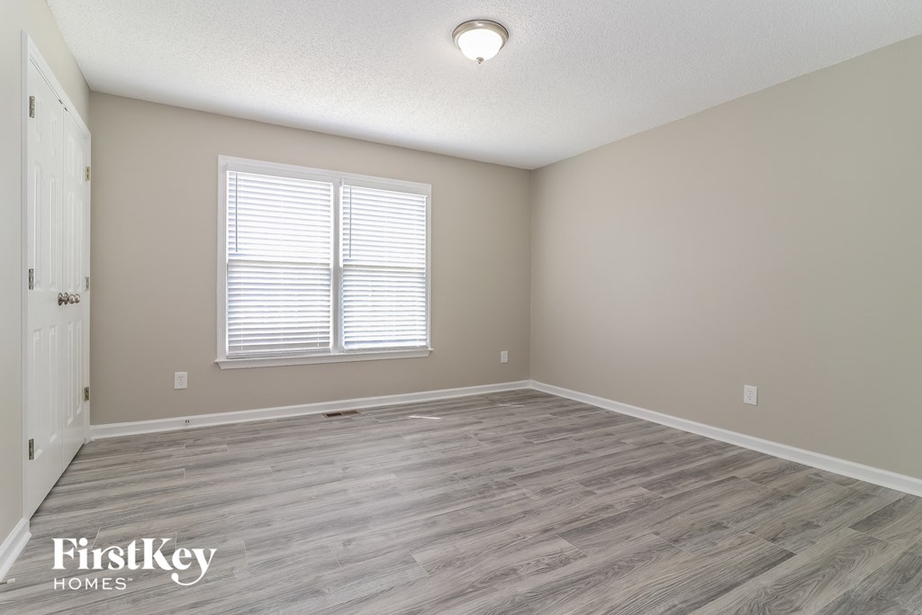 the spacious living room with wood flooring and a window