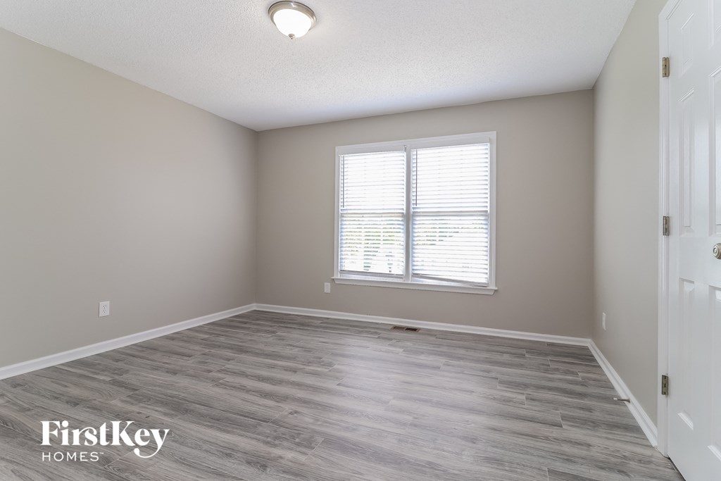 the spacious living room with wood flooring and a large window