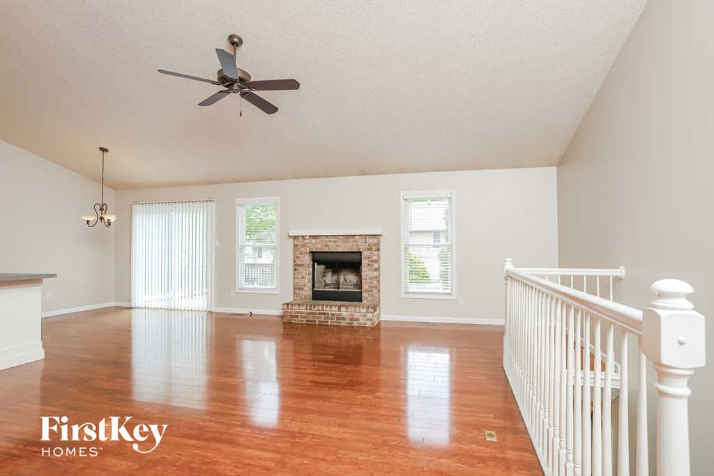 an empty living room with a fireplace and a ceiling fan