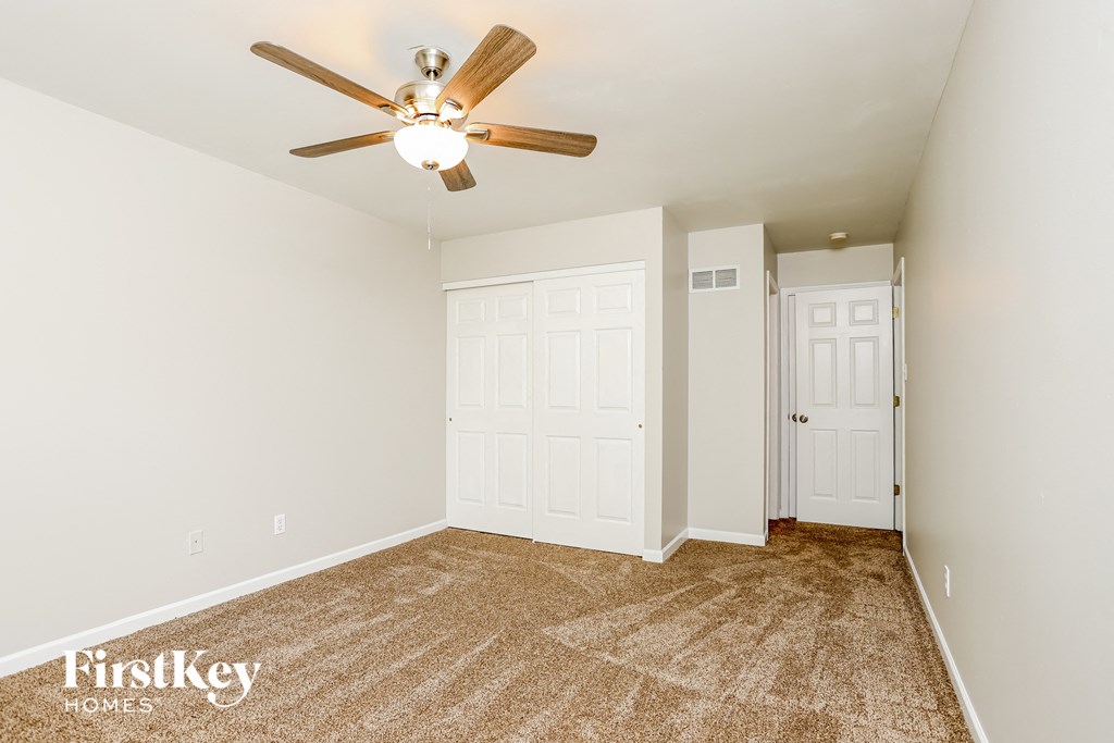 a bedroom with a ceiling fan and a door to a closet