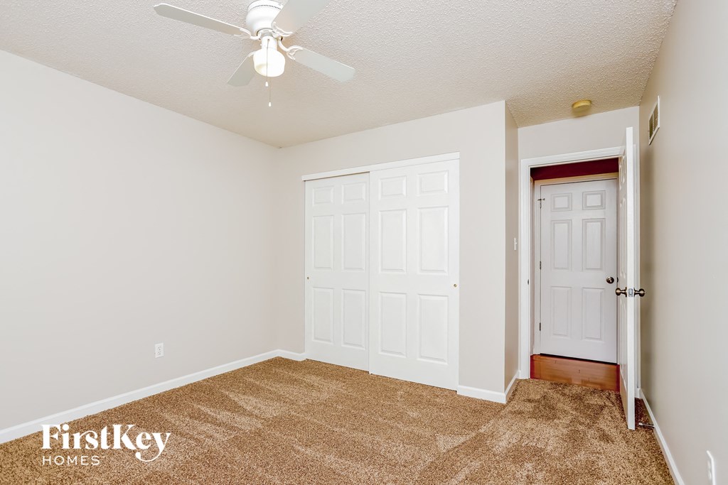 a bedroom with a carpeted floor and a ceiling fan