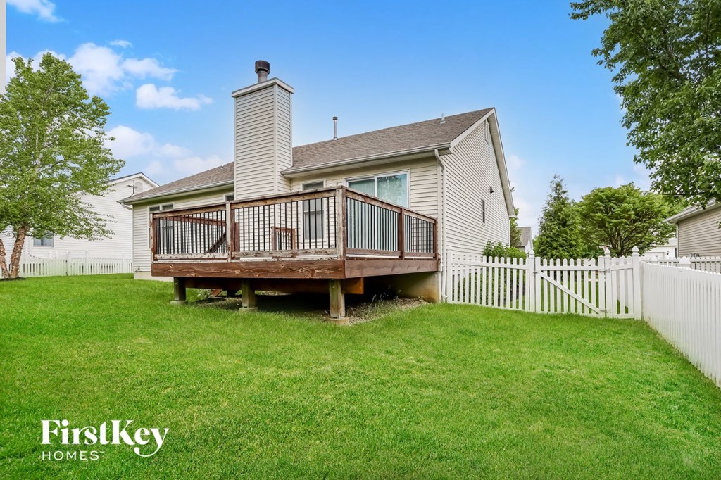 a backyard deck with a white fence and a house