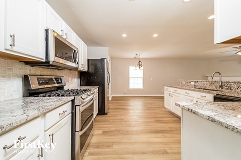 A kitchen with white cabinets and a black refrigerator.