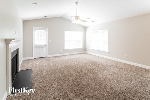 A living room with a carpet floor and a ceiling fan.