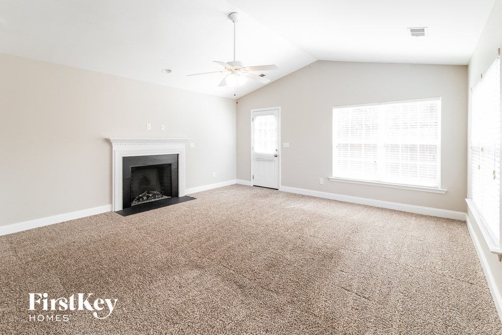 A spacious room with a fireplace and a ceiling fan.