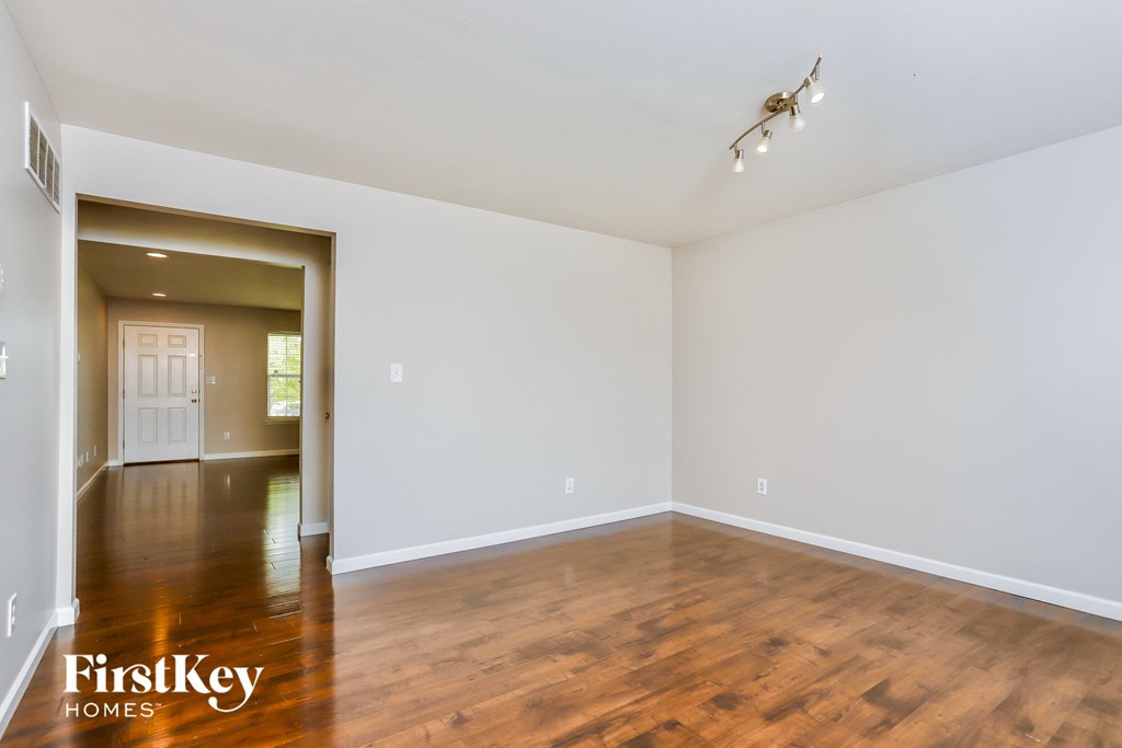 the living room and dining room of an empty house with wood flooring