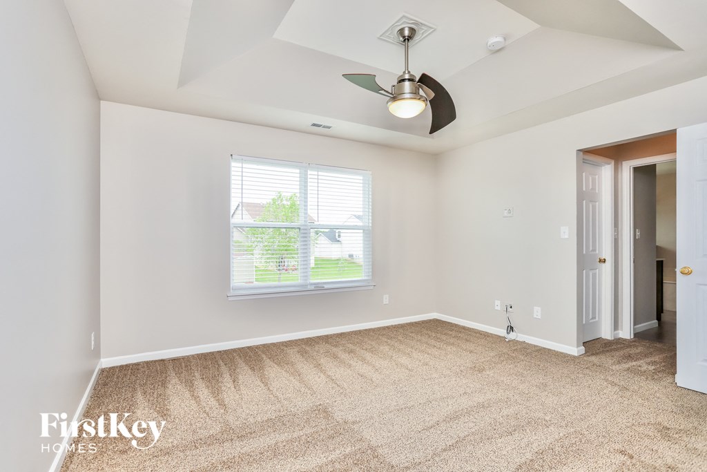 an empty living room with a ceiling fan and a window