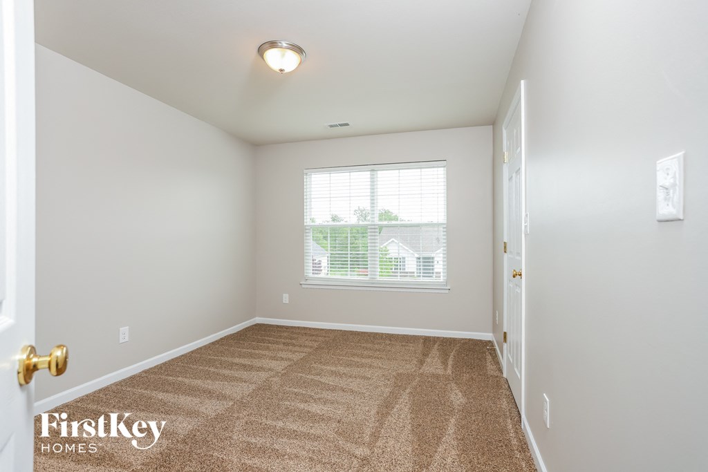 a spacious bedroom with carpet and a large window