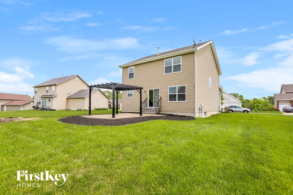 a house with a yard and a pergola in front of it