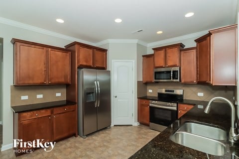 A kitchen with brown cabinets and a black counter top.