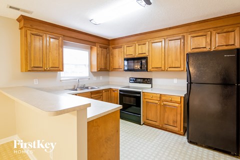 A kitchen with wooden cabinets and a black refrigerator.