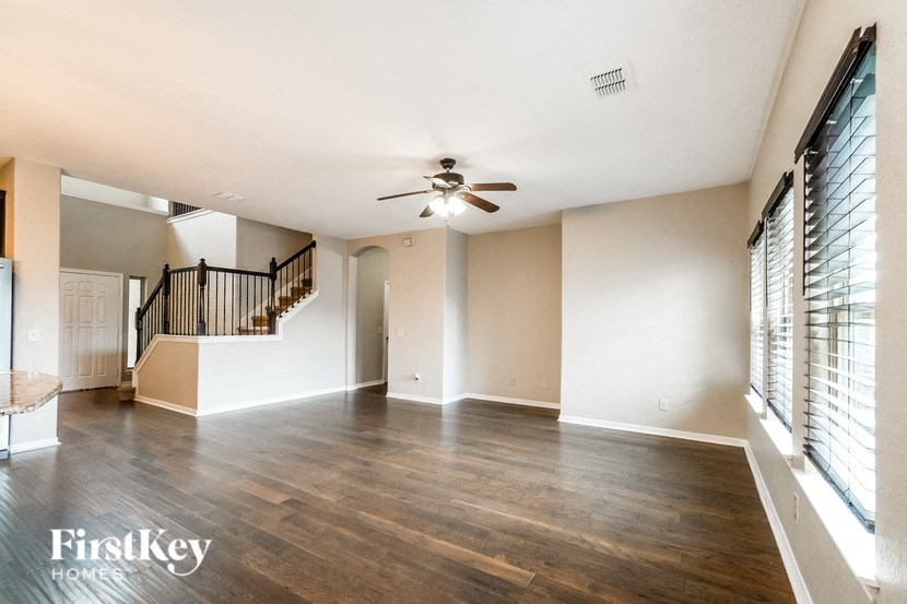 A spacious room with wooden floors and a ceiling fan.