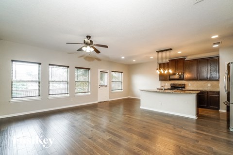 A spacious kitchen and living room with hardwood floors and a ceiling fan.