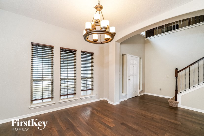 A chandelier hangs over a hardwood floor in a spacious room.