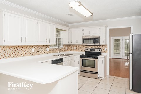 A kitchen with white cabinets and a black fridge.