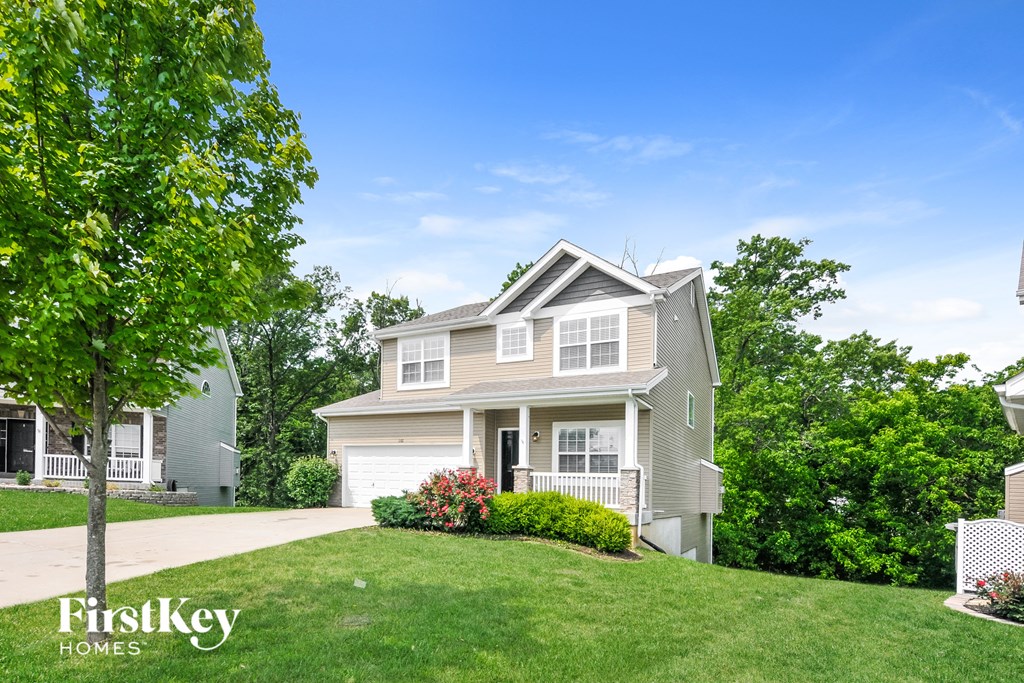 a house on a hill with a lawn and trees