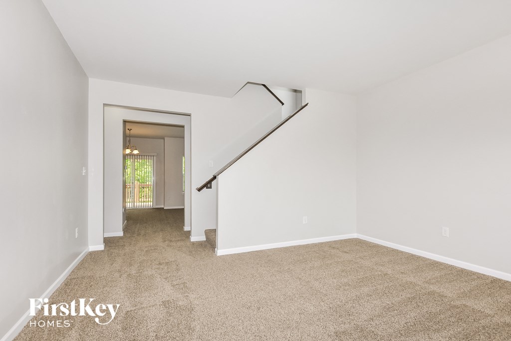 a living room with a carpeted floor and a staircase