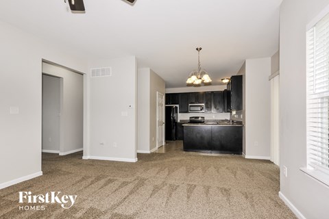 a spacious kitchen with black cabinets and white walls and carpeted flooring