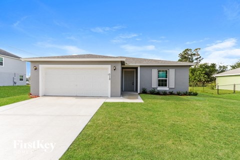 A house with a garage and a fence in the front yard.