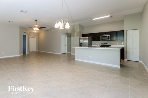 A spacious kitchen and living room with a white kitchen island and a ceiling fan.