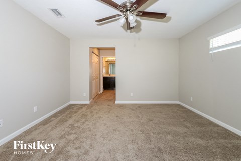 A spacious room with a ceiling fan and a doorway leading to another room.