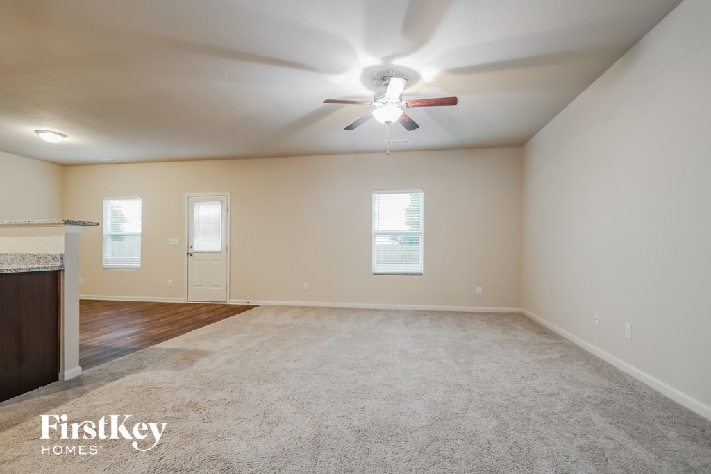 A spacious room with a carpeted floor and a ceiling fan.