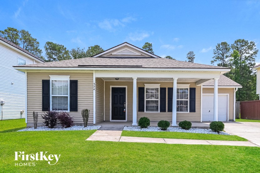 a home with black shutters and a lawn in front of it