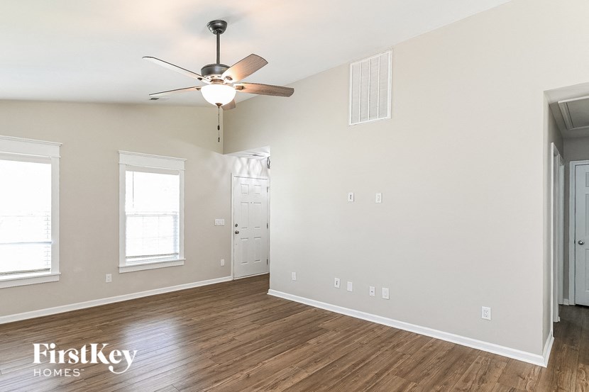 the living room and dining room of an empty house with a ceiling fan