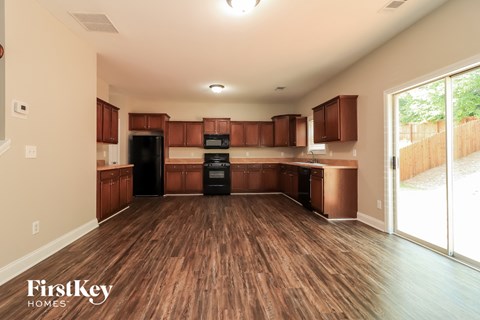 A kitchen with wooden floors and brown cabinets.