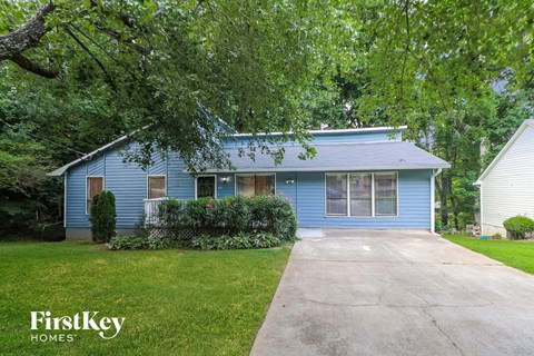 a blue house with a driveway and a tree