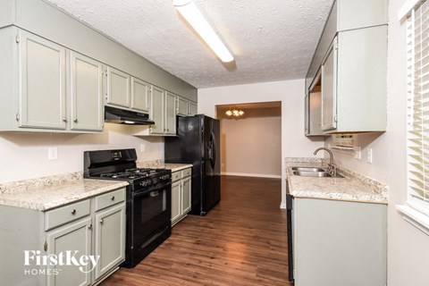 a kitchen with white cabinets and black appliances and a wood floor